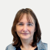 Porträtaufnahme von Ulrike Hecht-Ozlsberger, zuständig für Sozialarbeit in der Fachstelle Wohnen sowie Koordinatorin des Wicky Teams bei BALANCE. Sie blickt mit einem sanften Lächeln in die Kamera. Sie hat braunes, schulterlanges Haar mit einem lockeren Pony und trägt eine blaue Jeansjacke über einem dunklen Oberteil sowie eine feine Halskette vor einem neutralen, hellen Hintergrund.