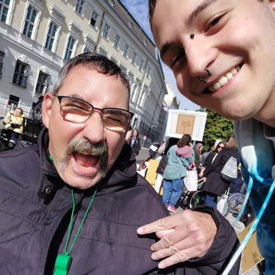 Ein Nutzer und ein Betreuer von BALANCE nehmen gemeinsam an einer Demonstration für die Inklusion von Menschen mit Behinderung teil.