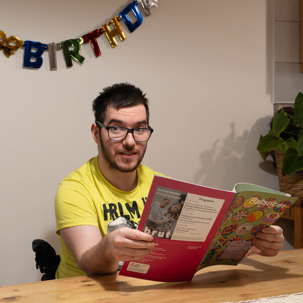 Bewohner Adam sitzt am Tisch und liest die Zeitschrift Balancer.