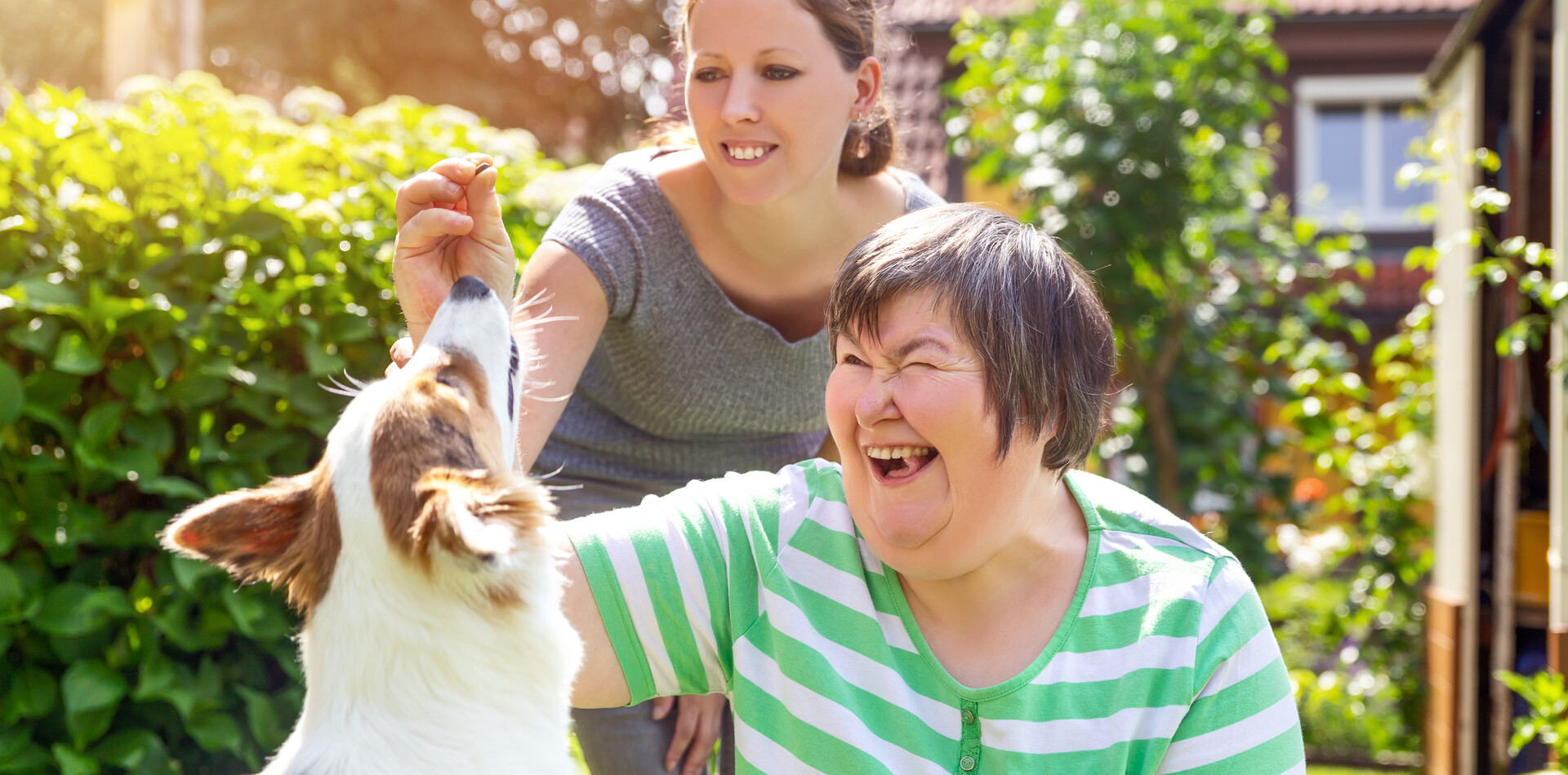 Tagesstrukturen für Menschen mit Behinderung © BALANCE Zwei Frauen spielen mit einem Hund im Garten einer Tagesstruktur für Menschen mit Behinderung.