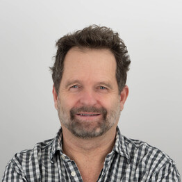 Mag. Michael Katschnig Porträtaufnahme von Mag. Michael Katschnig, Mitarbeiter der Stabstelle Personal bei BALANCE. Er blickt freundlich lächelnd in die Kamera. Er hat dunkles, leicht gelocktes Haar und einen gepflegten Dreitagebart. Er trägt ein schwarz-weiß kleinkariertes Hemd vor einem neutralen, hellgrauen Hintergrund.