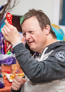 Ein Mann hält eine Geschenktüte mit Schokoladen-Nikolaus in der Hand.