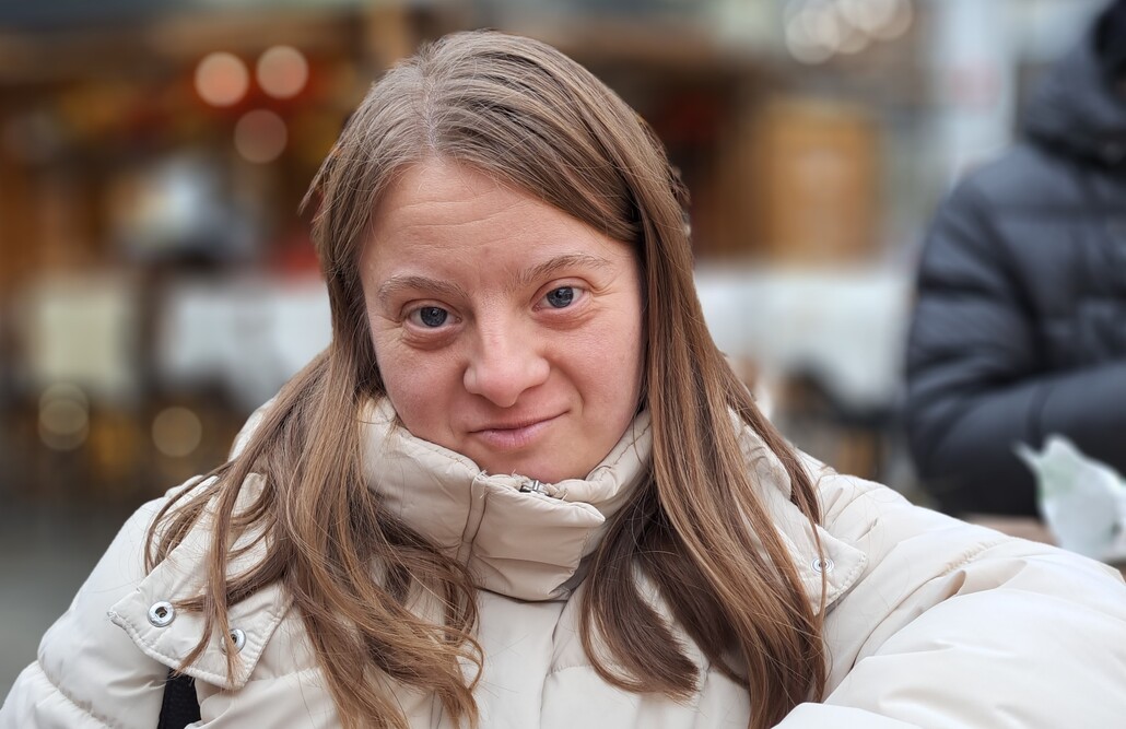 Mobile Betreuung I BALANCE Eine junge Frau mit Behinderung und langen braunen Haaren blickt selbstbewusst in die Kamera.