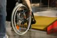 Rollstuhlfahrer steht vor gelber Rampe
