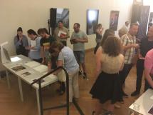 BesucherInnen stehen um einen Tisch mit Computer und betastbaren Reliefen